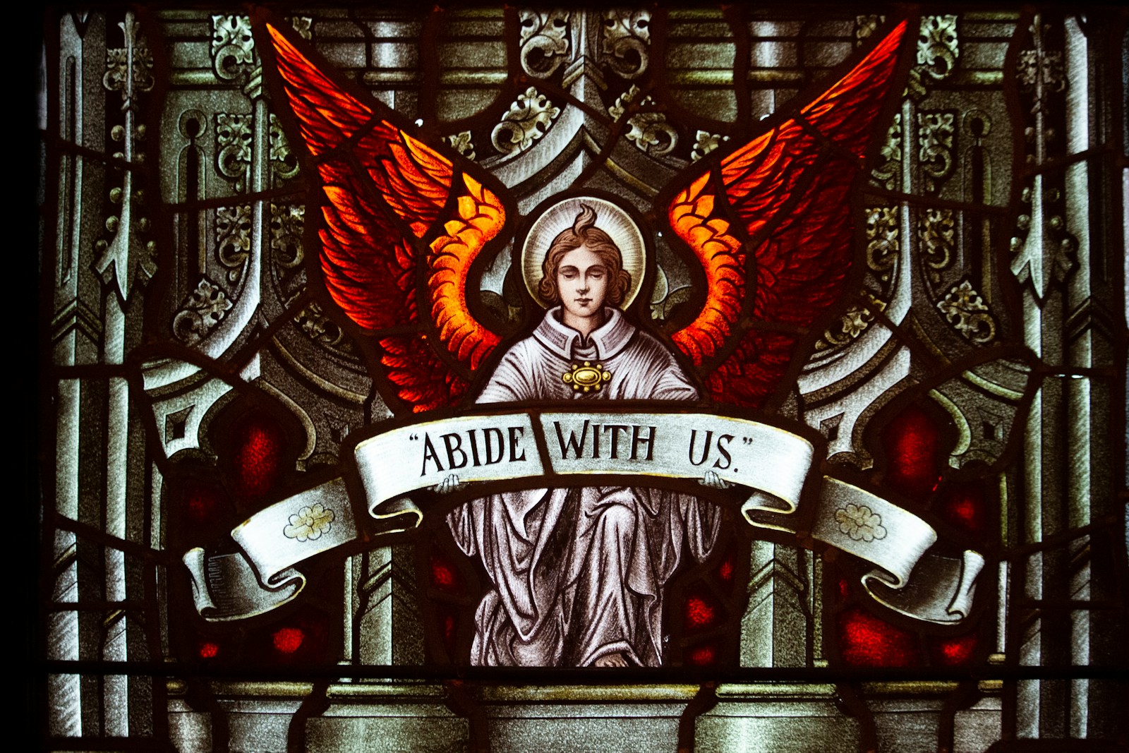 a stained glass window with an angel holding a banner